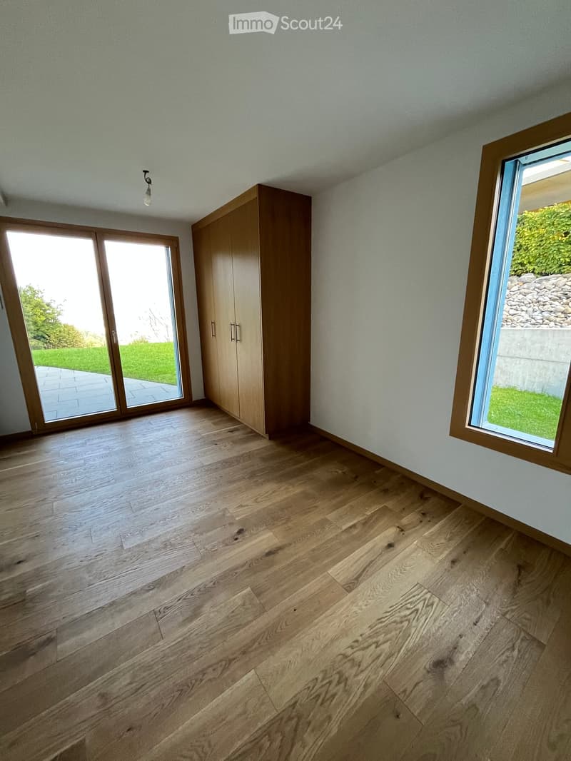 Empty room with wooden floors, wooden wardrobe, sliding doors, windows