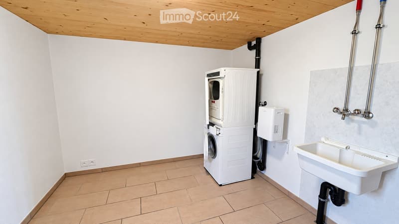 Clean, modern bathroom with a white washing machine, a white sink, and a tiled floor.