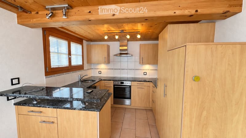 Modern kitchen with wooden cabinets, granite countertops, stainless steel appliances, and a range hood. Features a sink, faucet, and built-in oven.