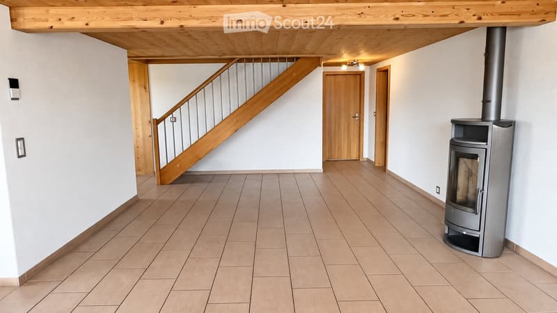 Empty hallway with tiled floor, wooden staircase, and a modern wood-burning stove.