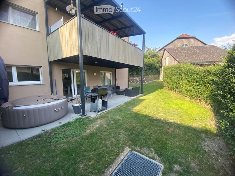 Garden with a hot tub, outdoor seating area, and a covered balcony with a view of the house.