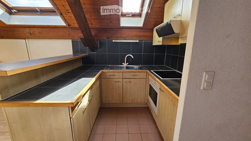 Modern kitchen with wooden cabinets, black tiled backsplash, stainless steel sink, and electric stovetop.
