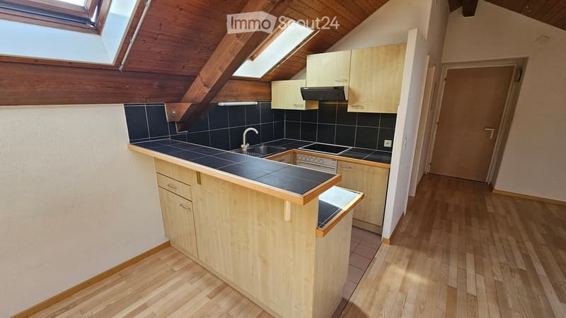 Modern kitchen with wooden cabinets, a central island, and black tiled countertops. Features include a sink, faucet, oven, and range hood, with skylights providing natural light.