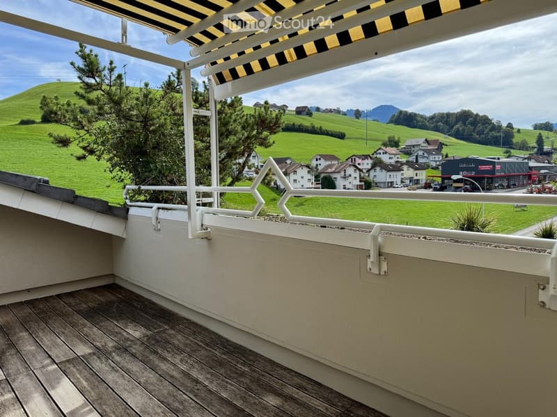 Balcony with wooden decking, white railing, and scenic countryside view.