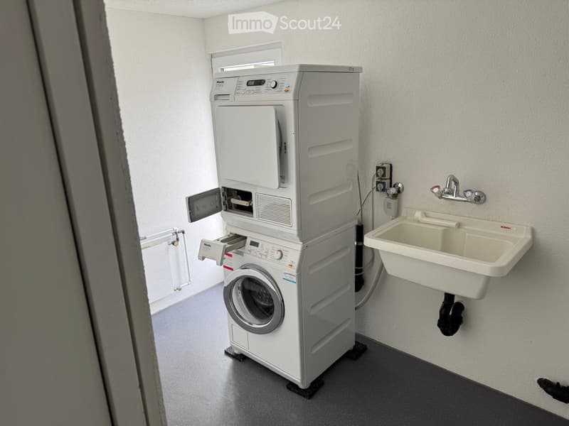 Bathroom with a stacked washing machine and a sink.