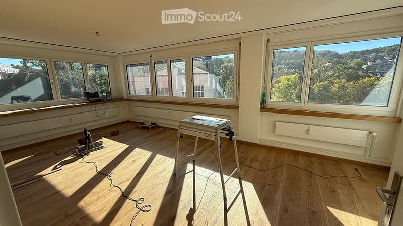 Empty room with wooden flooring, large windows, and natural light. No furniture or equipment present.