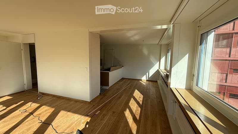 Empty room with wooden flooring, white walls, and large windows allowing natural light. No furniture or equipment present.