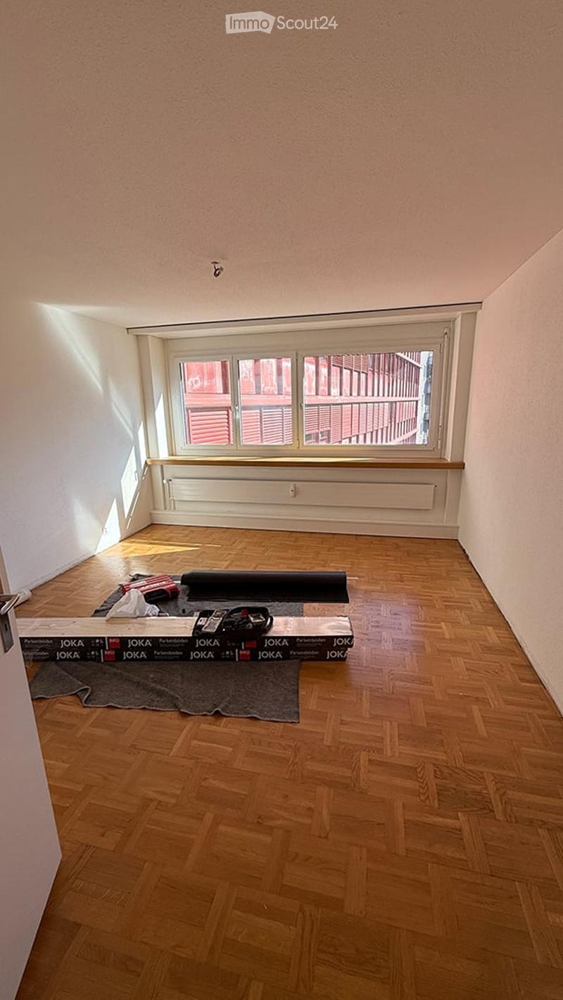 Empty room with wooden flooring, white walls, and large windows with blinds. No furniture or equipment present.
