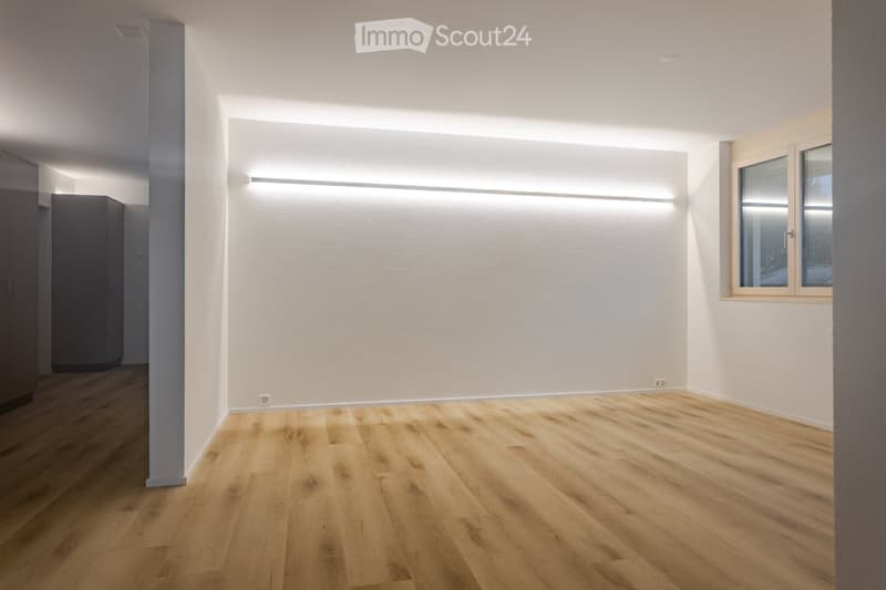 empty room with wooden floor, white walls, built-in ceiling light, window