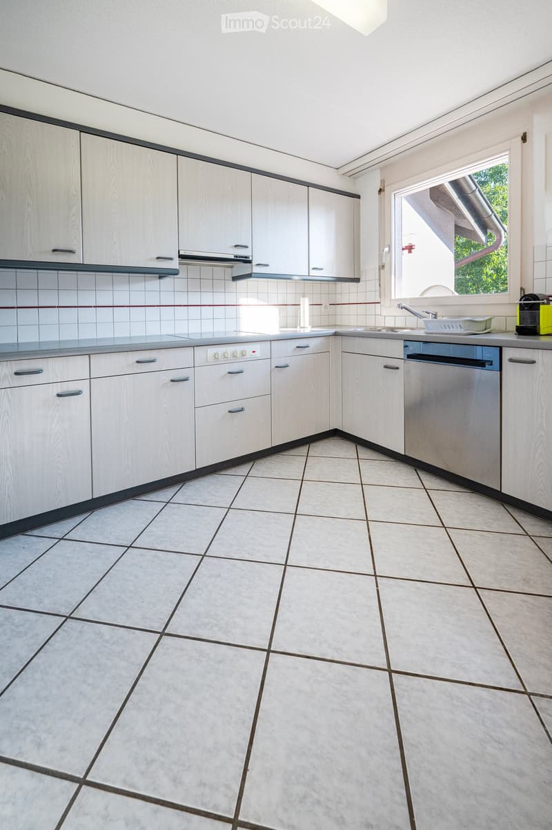 Modern kitchen with white cabinets, tiled backsplash, and tiled floor. Features a sink, faucet, and dishwasher.