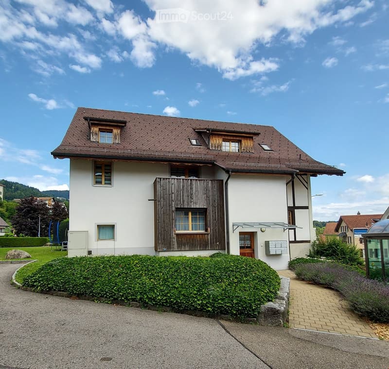 2 story house, white walls, brown roof, wooden balcony, garden, driveway