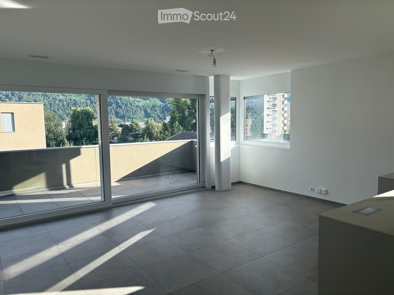 Empty room with tiled floor, large glass sliding doors leading to a balcony, and a view of greenery and buildings.