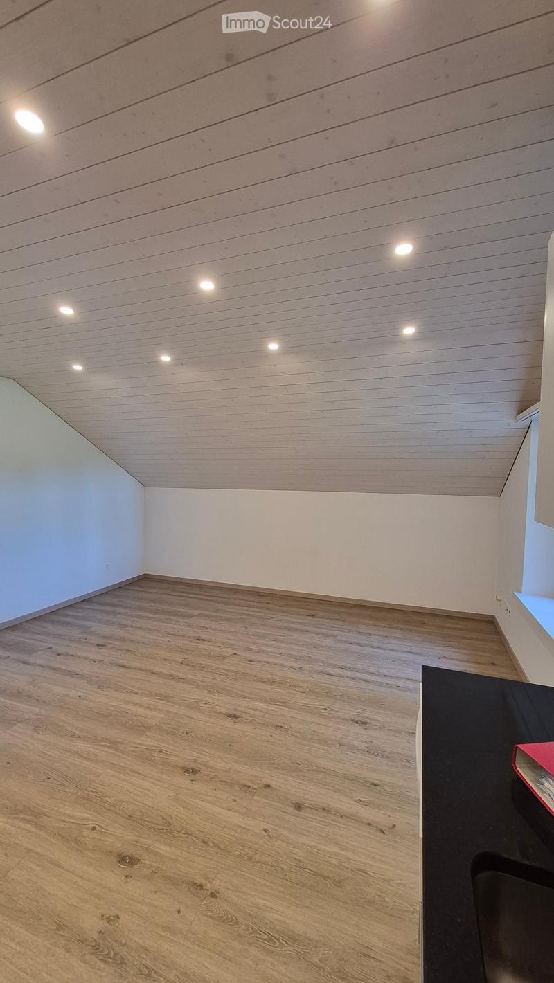 Empty room with wooden flooring and white walls, featuring recessed ceiling lights and a small window on the right side.