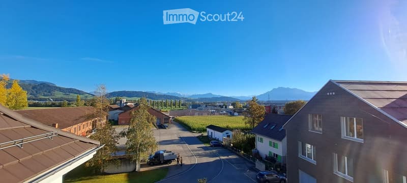 A suburban residential area with modern houses, a clear blue sky, and distant mountains in the background.