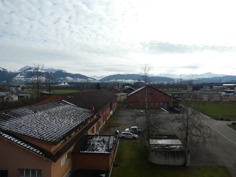 A multi-building complex with a parking lot, surrounded by a rural landscape with mountains in the background.