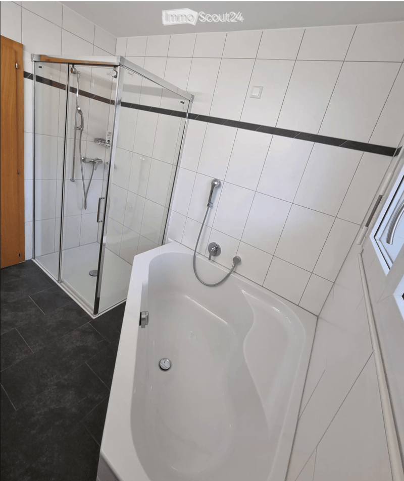 Modern bathroom with a white bathtub, glass-enclosed shower, and chrome fixtures.