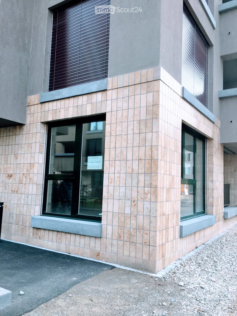 Modern building exterior with tiled facade, large windows, and a sign on the window.