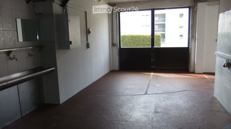 Empty room with a sink and cabinet on one side, a large doorway leading to an outdoor area with greenery visible.