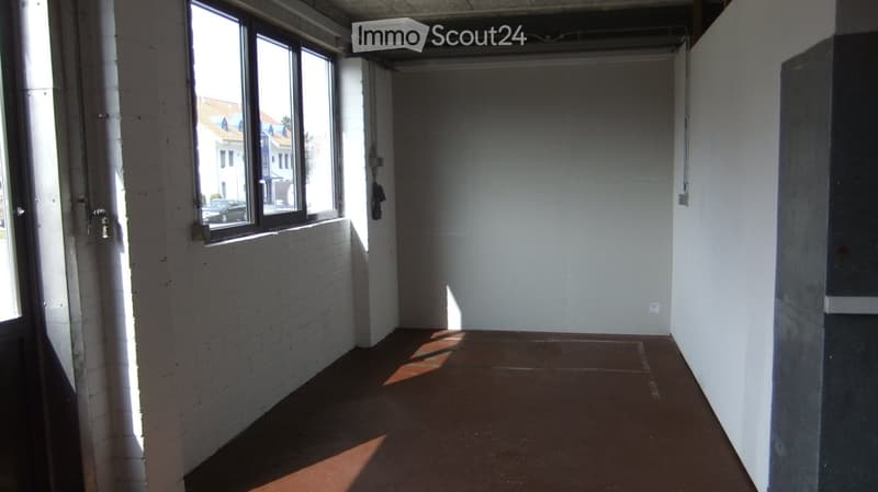 Empty hallway with exposed brick wall, large window, and concrete floor.