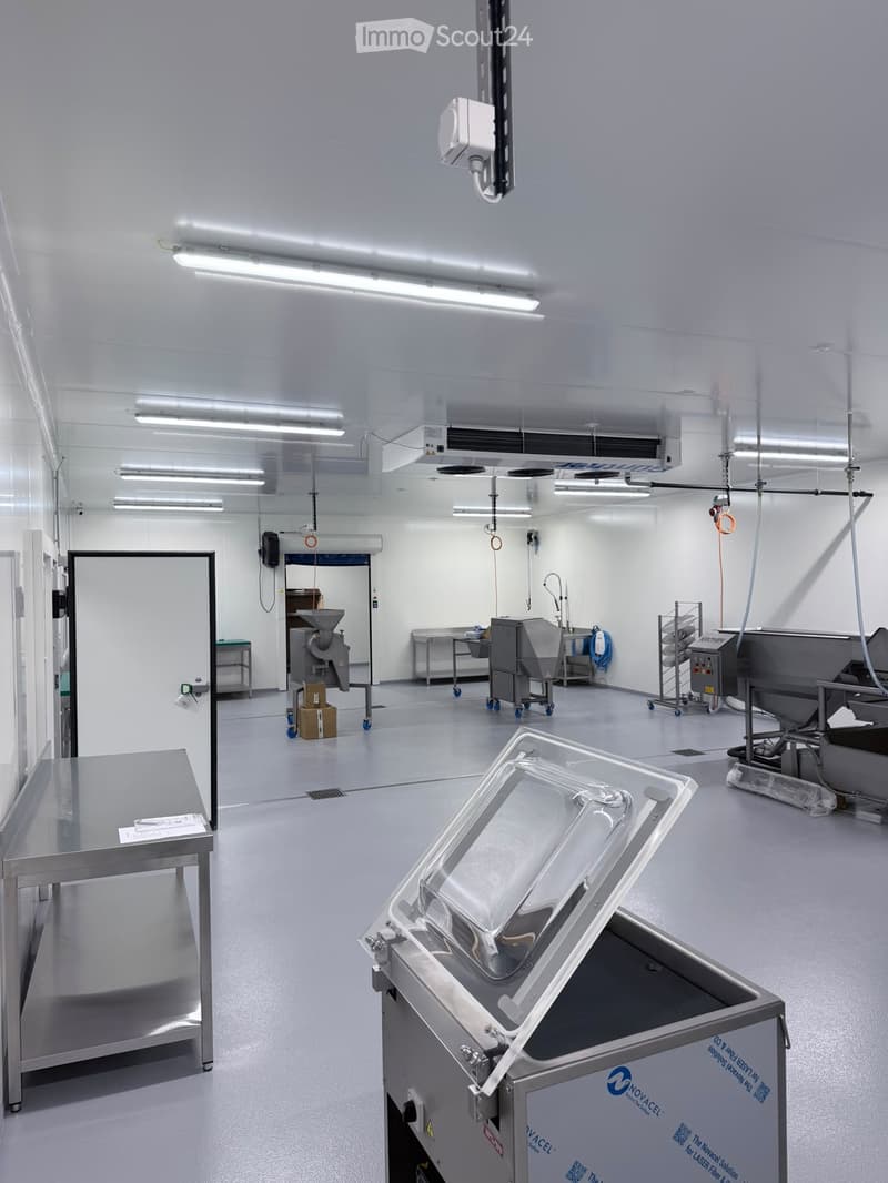 Clean, modern industrial room with stainless steel equipment, tables, and a large open space.