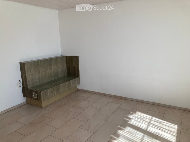 Empty room with light-colored walls, tiled floor, and a built-in bench along one wall.