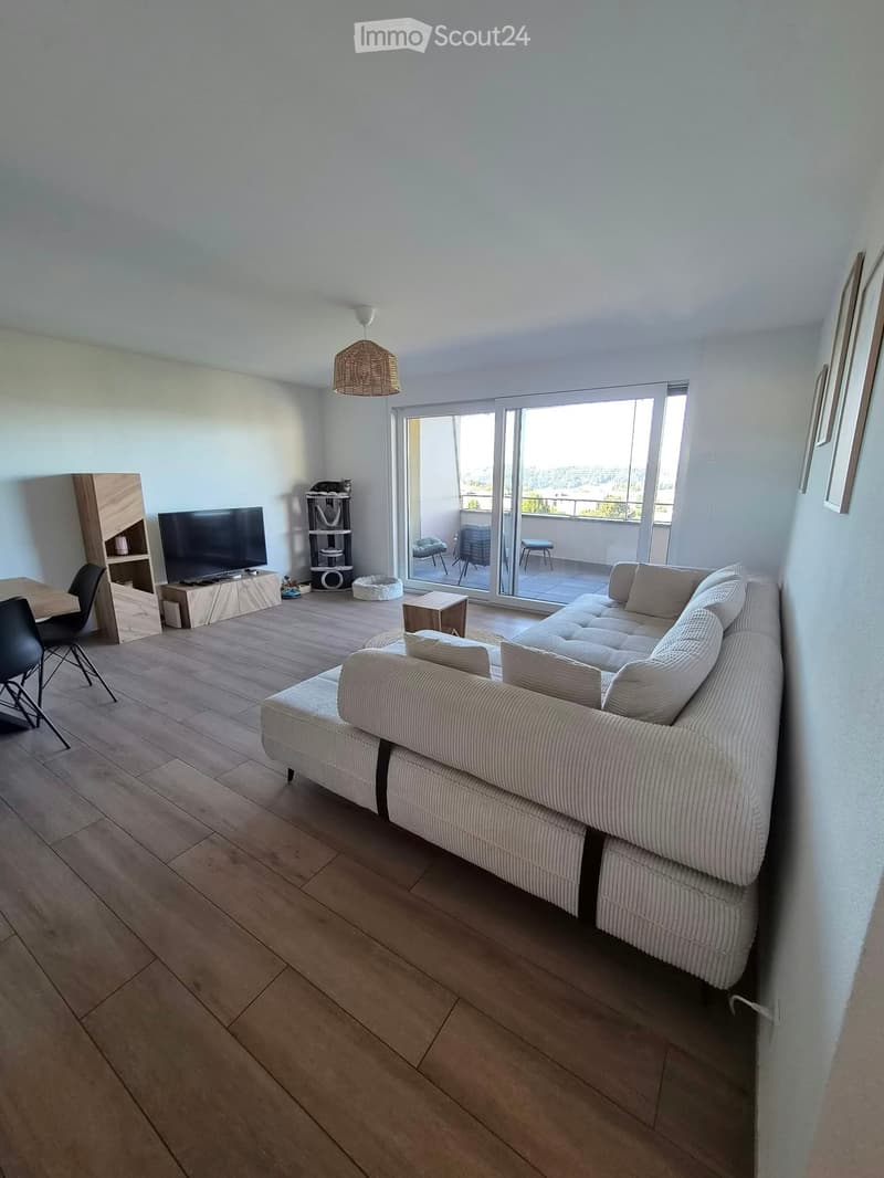 Modern living room with a large sectional sofa, coffee table, dining area, cat tree, and access to a balcony.