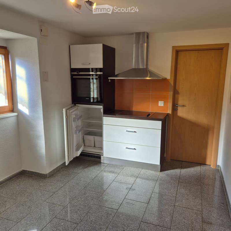 Modern kitchen with white cabinets, stainless steel appliances, and a tiled floor. Features include a refrigerator, oven, and range hood.