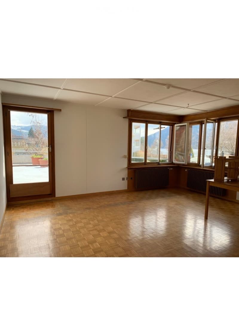 Empty room with wooden flooring, large windows, and a door leading to an outdoor area. No furniture or equipment is present.