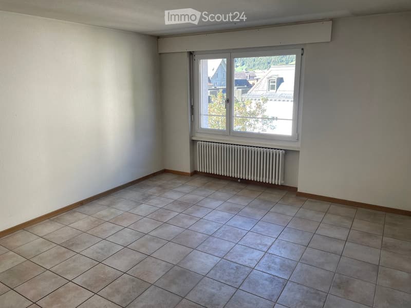 Empty room with tiled floor, white walls, and a window with a radiator below it.