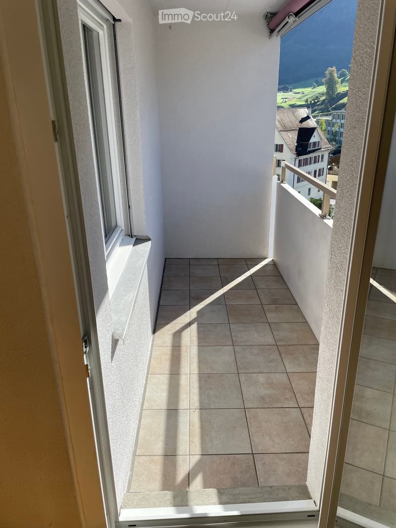 Balcony with tiled floor, white walls, metal railing, and scenic countryside view.