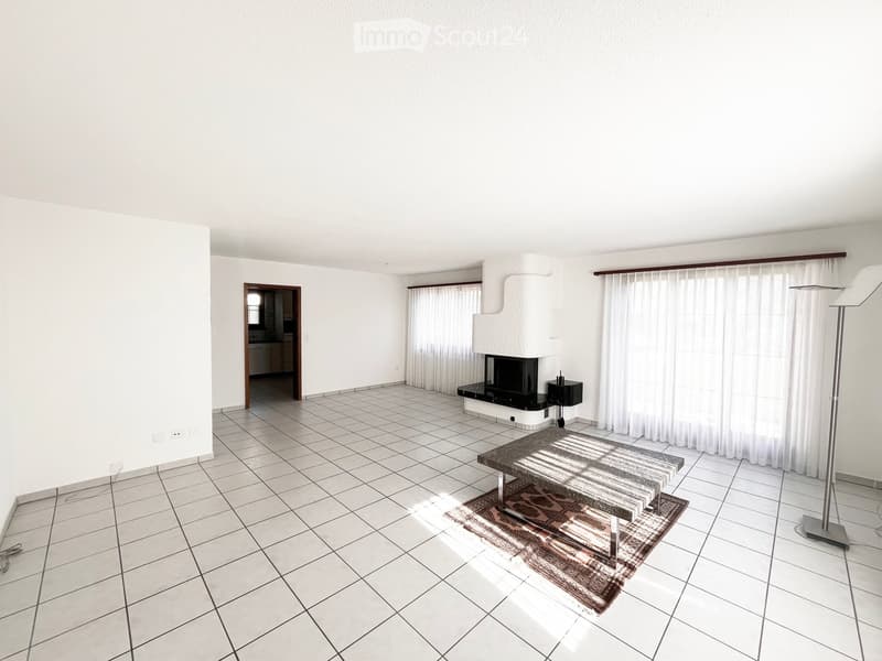 Bright living room with tiled floor, fireplace, coffee table, and floor lamp.