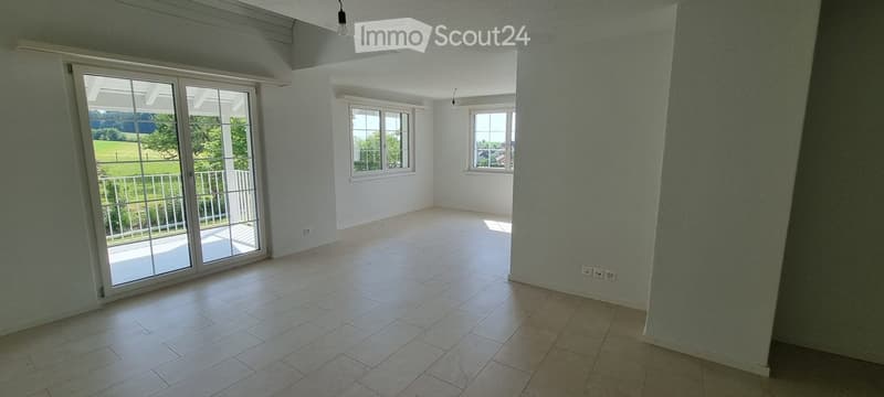 Empty room with tiled floor, large sliding glass door leading to a balcony, and two windows allowing natural light.