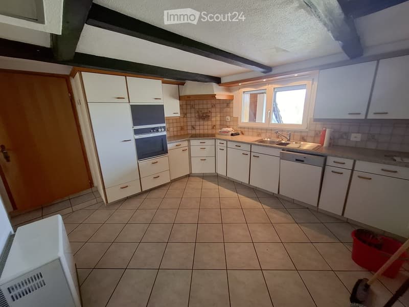 Bright kitchen with white cabinets, tiled floor, and modern appliances including an oven, sink, and dishwasher. Natural light from windows illuminates the space.