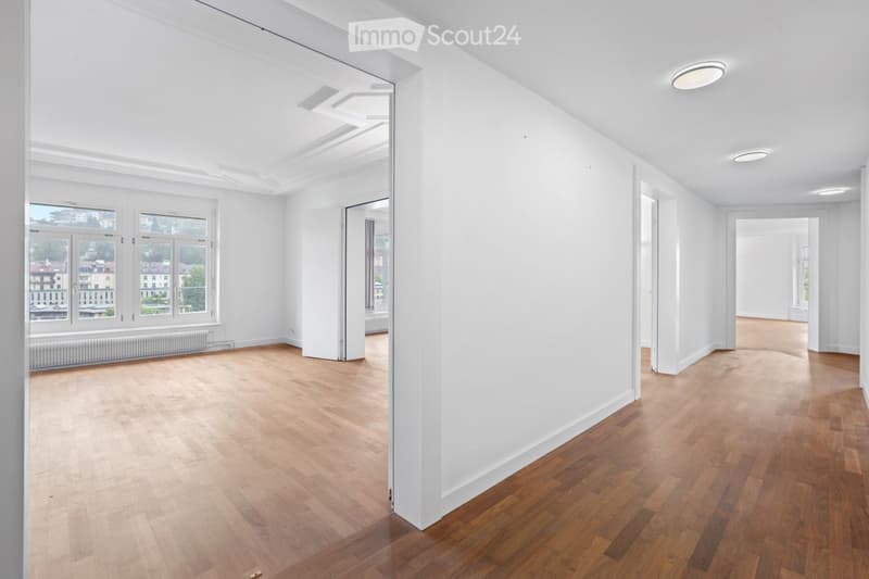 Empty room with wooden flooring, white walls, large windows, and recessed lighting. No furniture or equipment present.