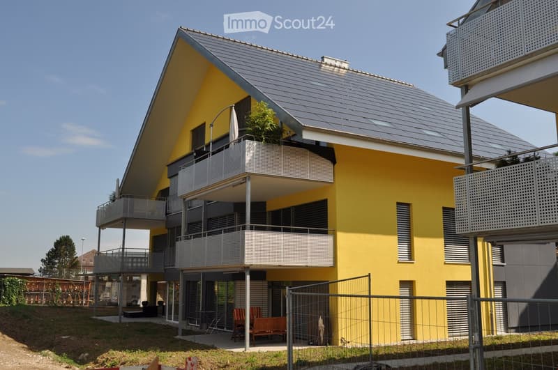 modern yellow building, multiple balconies, solar panels on the roof