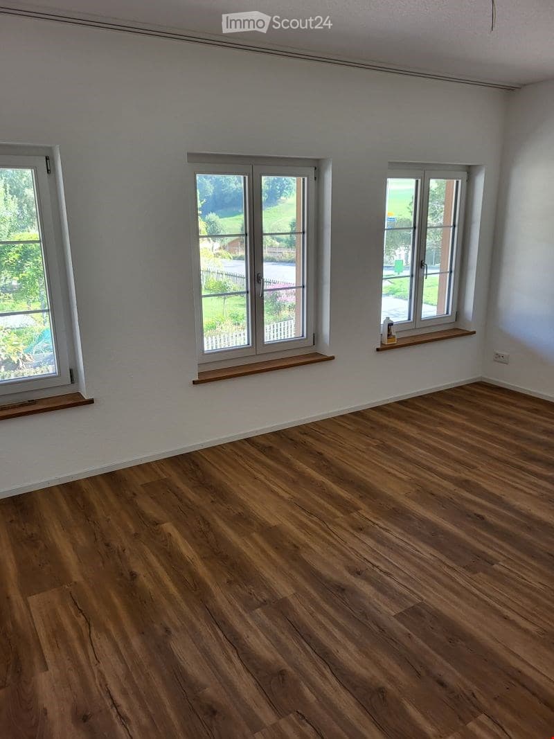 Empty room with wooden flooring, white walls, and three windows with wooden sills. No furniture or equipment present.