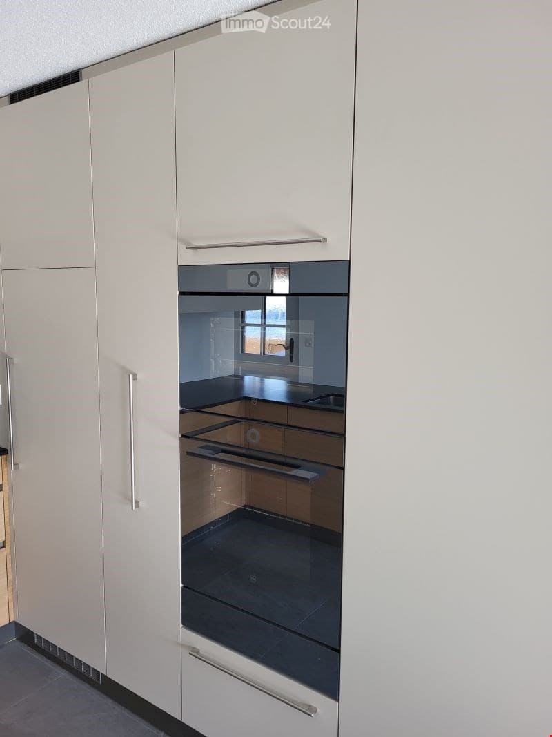 Modern kitchen with white cabinets and a built-in oven, featuring sleek design and contemporary finishes.