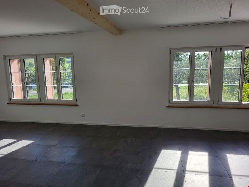 Empty room with light grey walls, large windows, and tiled floor. No furniture or equipment present.