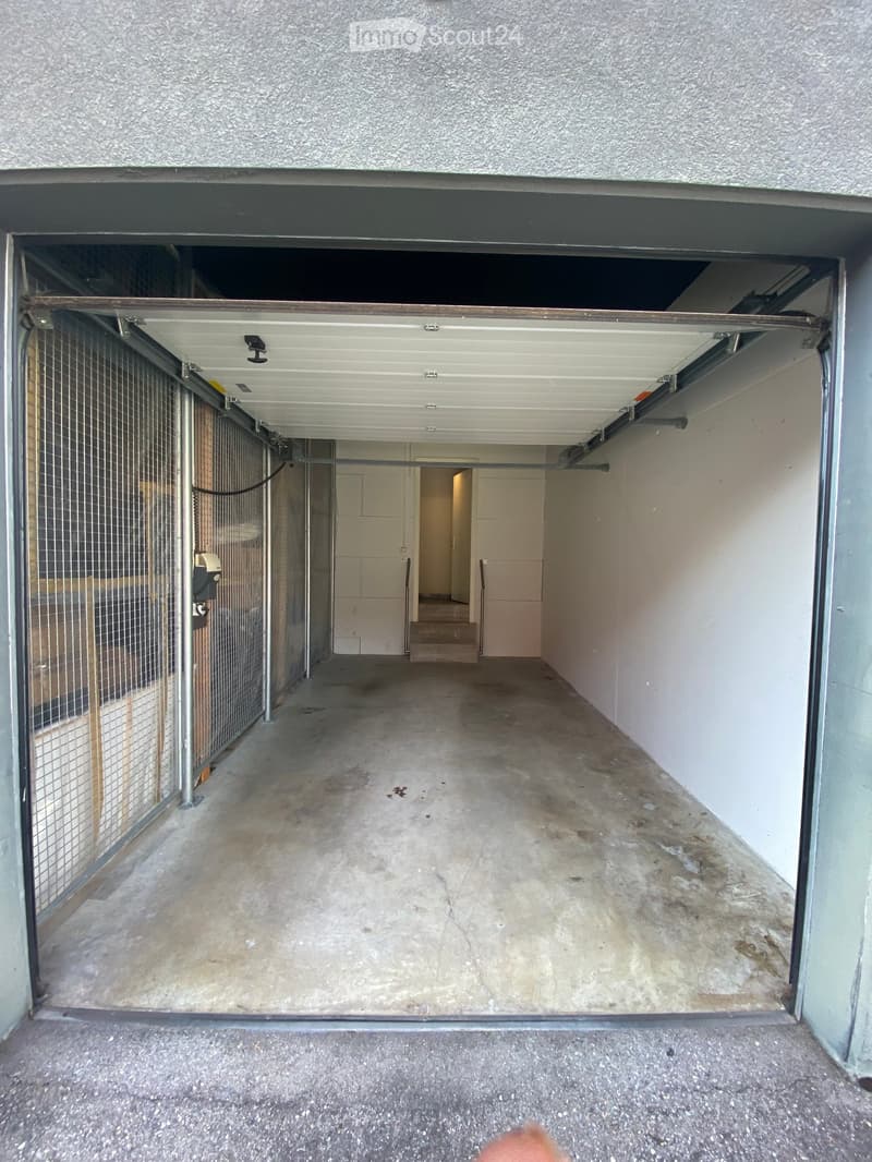 Empty concrete corridor with a gated area on the left and a doorway leading to another room at the end.