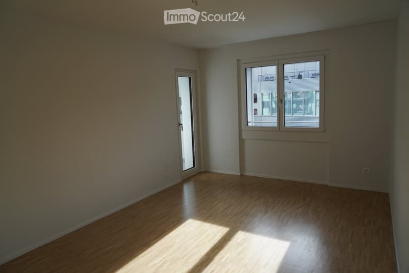 empty room with wooden floor, white walls, sliding door, and window