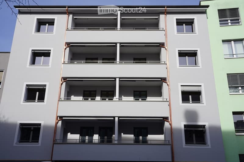 A grey apartment building with multiple balconies on every floor.