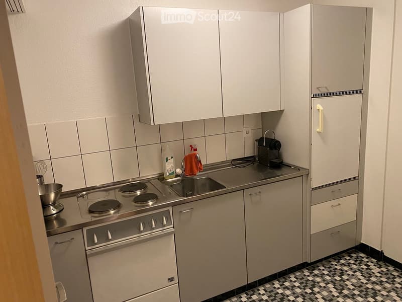 Modern kitchen with white cabinets, stainless steel appliances, and a tiled floor.