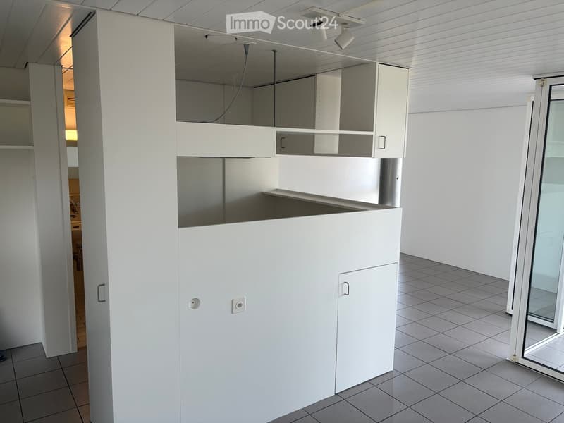 Empty room with white cabinetry, tiled floor, and a large glass door leading outside.