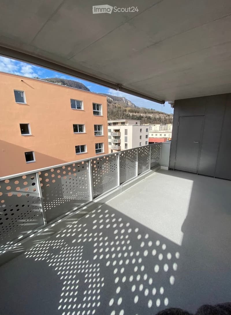 Balcony with modern metal railing, concrete floor, and scenic mountain view in the background.