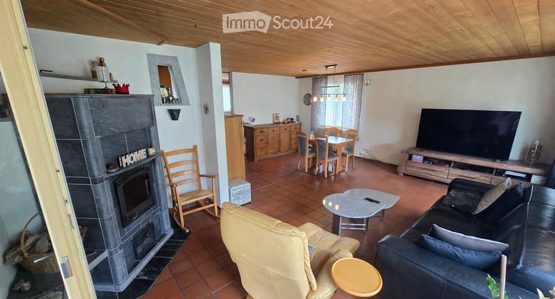Spacious living room with a fireplace, sofa, armchair, coffee table, dining area, and TV stand.