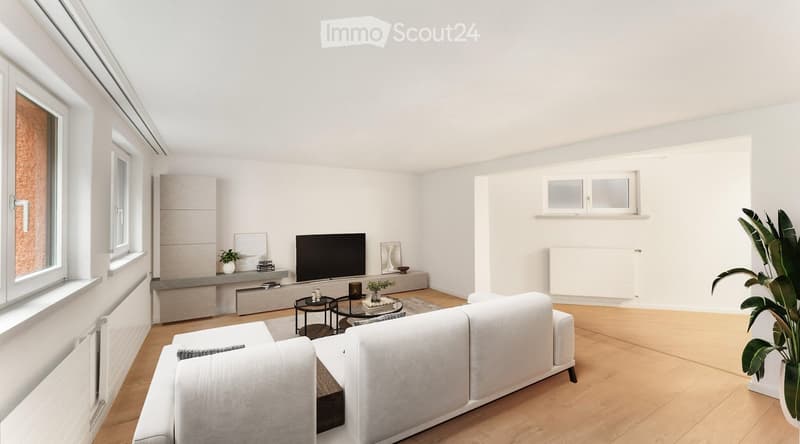 Bright living room with white walls, wooden flooring, a white sectional sofa, a coffee table, a television, side tables, and plants.