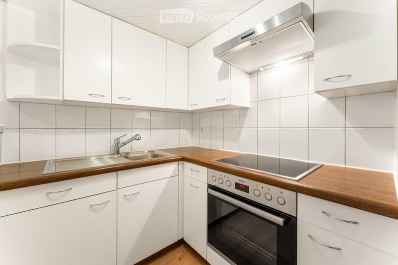 Modern kitchen with white cabinets, wooden countertops, stainless steel sink, and built-in oven.