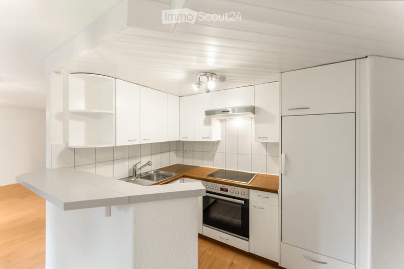 Modern kitchen with white cabinets, wooden countertops, stainless steel appliances, and a central island.