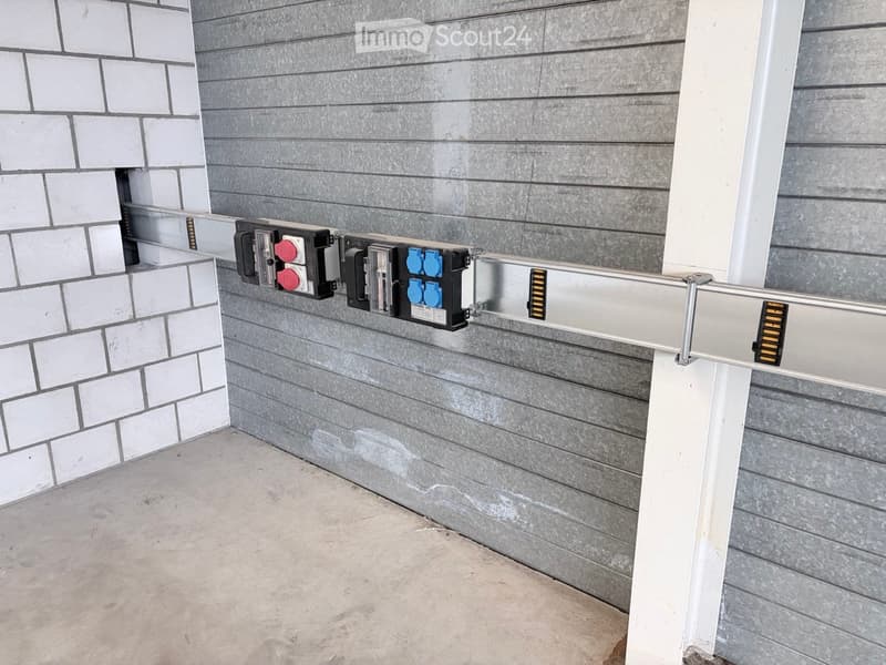 An outdoor electrical panel mounted on a grey wooden wall with switches and cables visible.