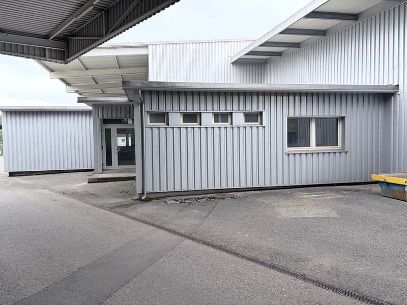 Modern industrial-style building with corrugated metal siding, large windows, and a covered entrance area.